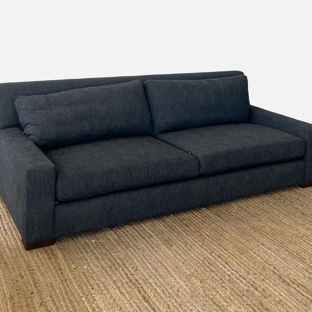 Dark fabric Reperch sofa with three seats, clean lines, and wooden feet on a natural woven rug.