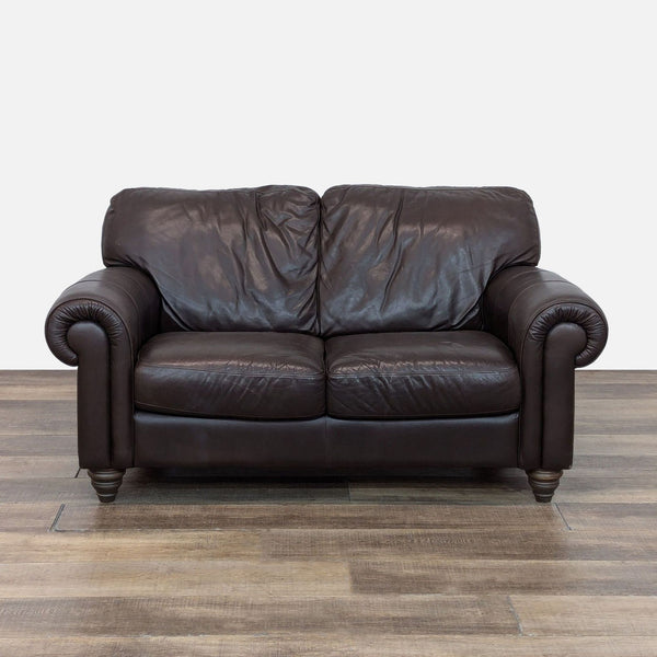 Natuzzi brown leather loveseat with rolled arms and turned wood bun feet.
