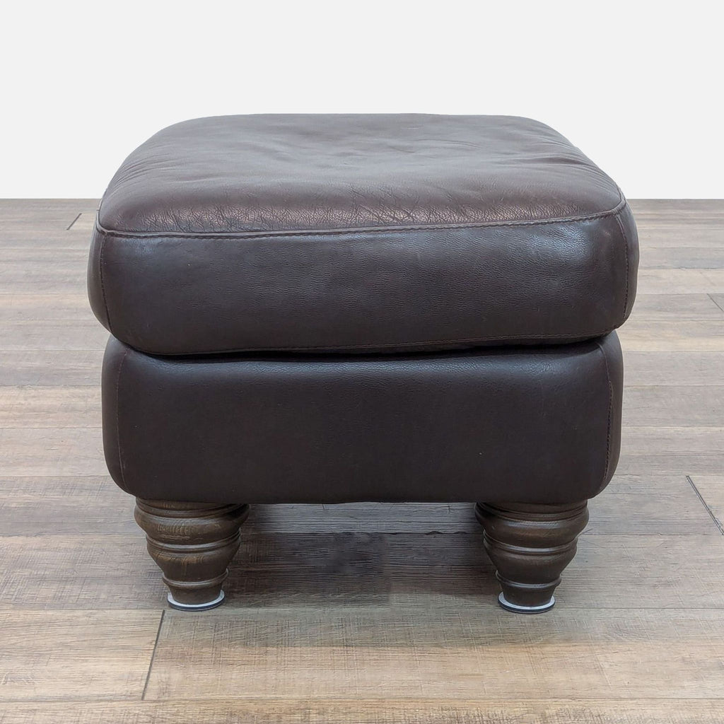 Natuzzi ottoman in classic brown leather upholstery, top view with elegant wooden feet.