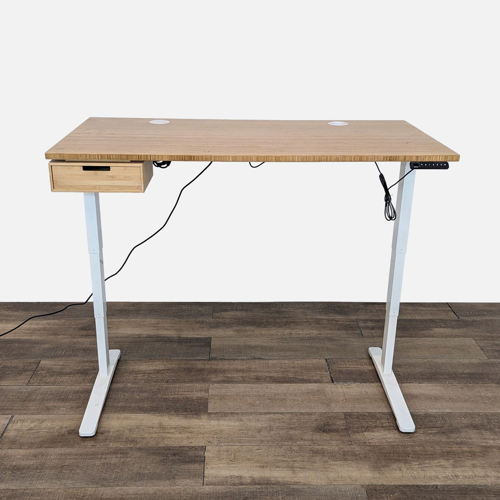 Uplift V2 standing desk with bamboo top, white T frame, drawer, grommets, and keypad.
