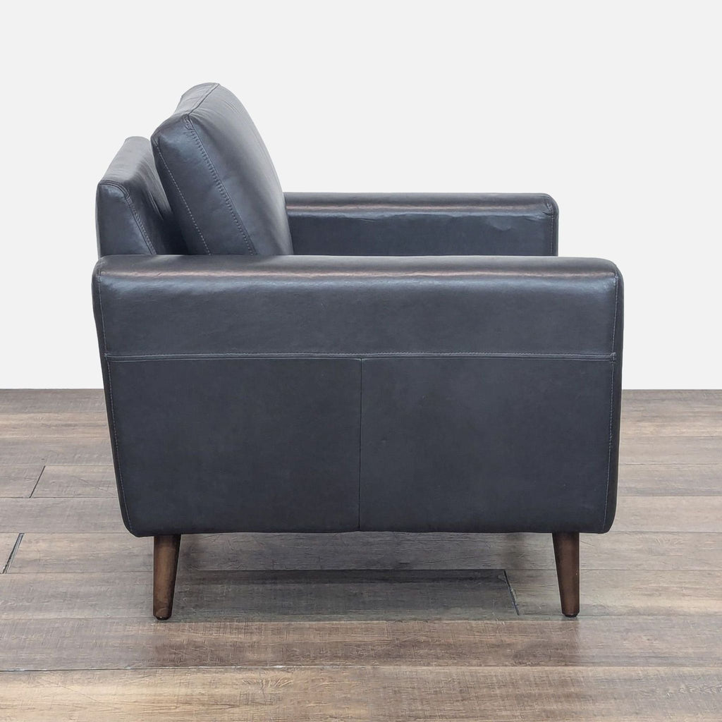 Side view of a Nomad lounge chair showcasing black leather and sleek track arms.