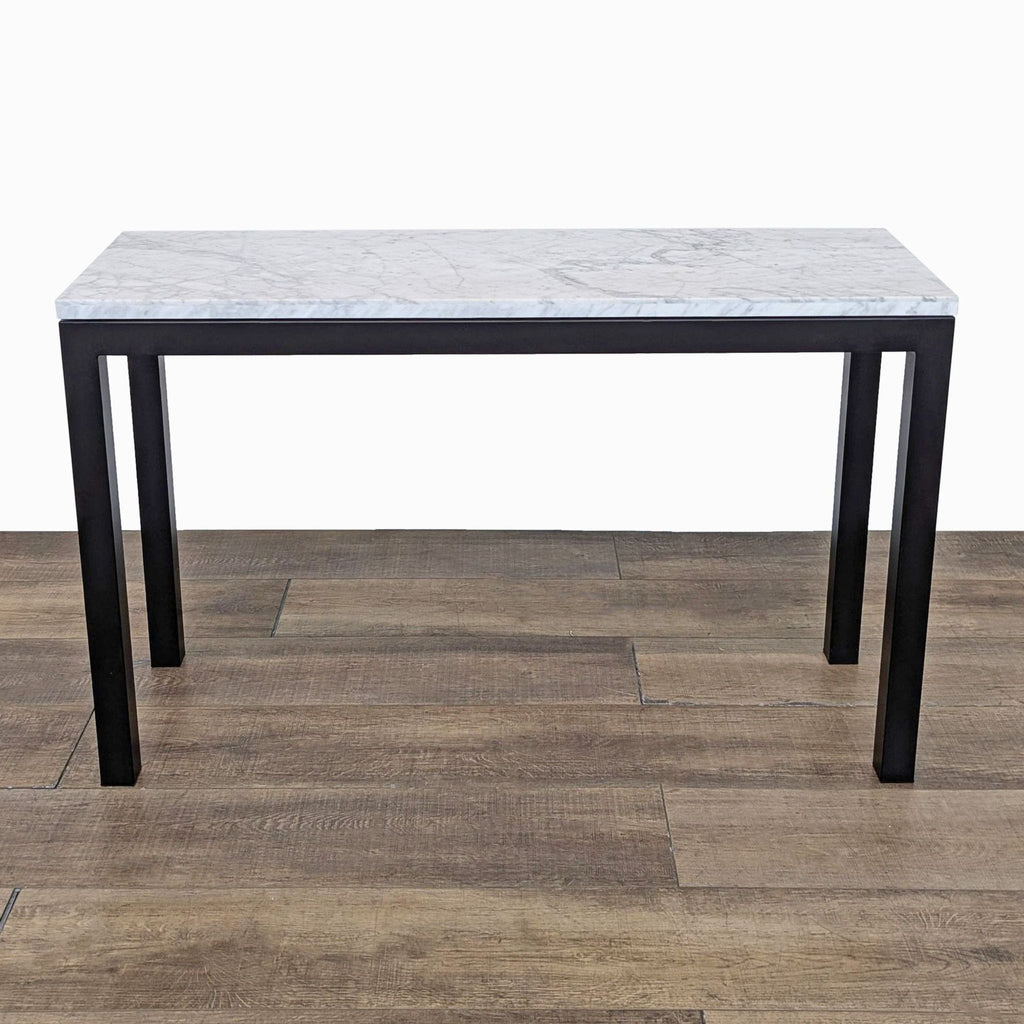 Crate & Barrel Parsons style table with steel legs and marble top, on wood floor.