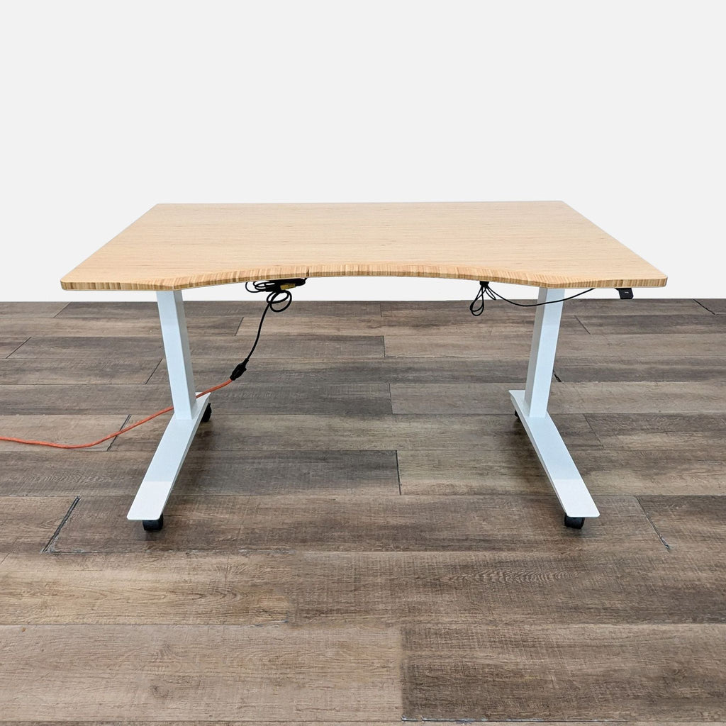 Adjustable desk with bamboo top, white base, and locking casters on wood floor.