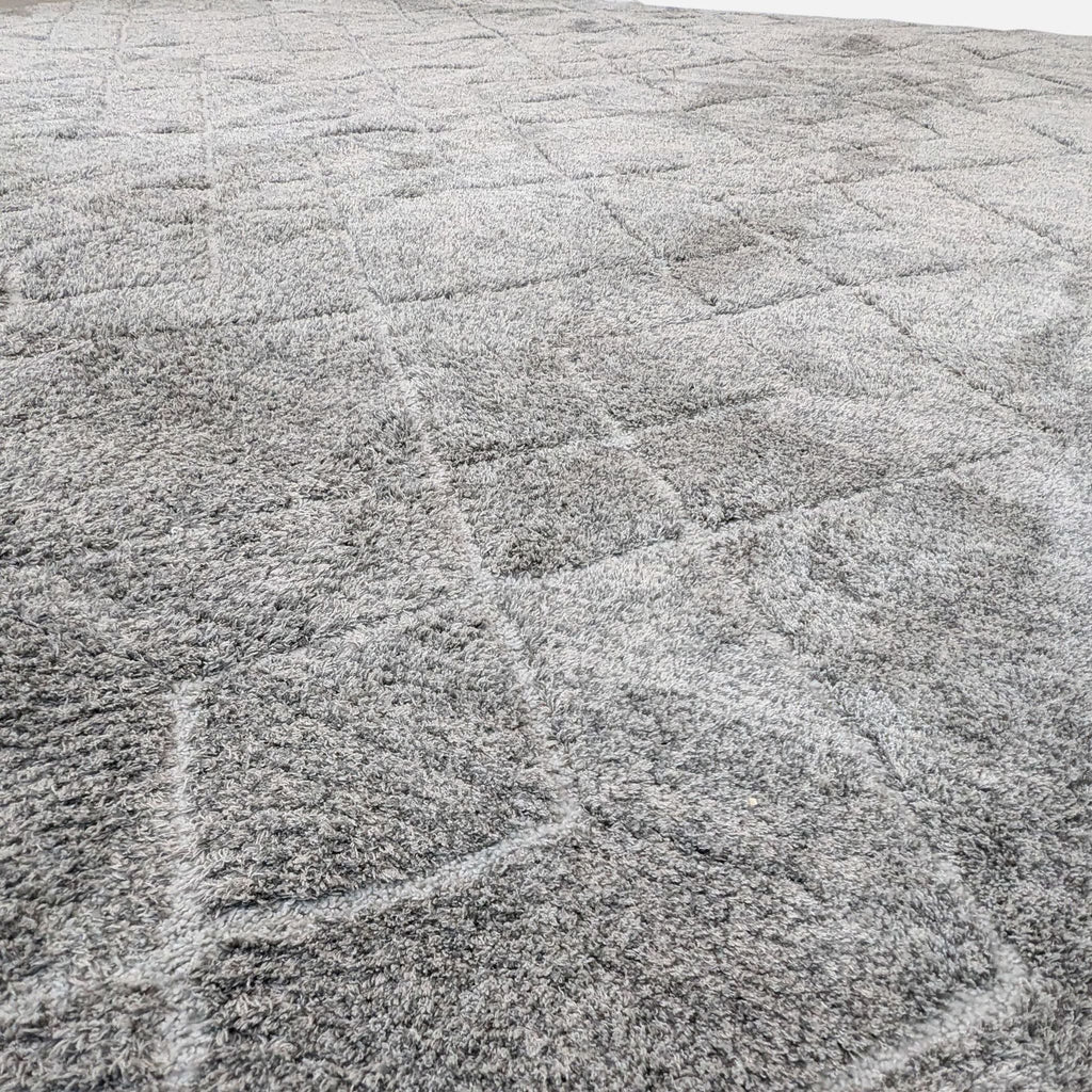 Close-up of a gray rug with thick pile and intricate diamond design.