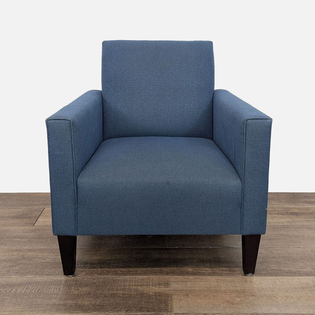 Modern blue lounge chair with tapered wooden legs, front view.