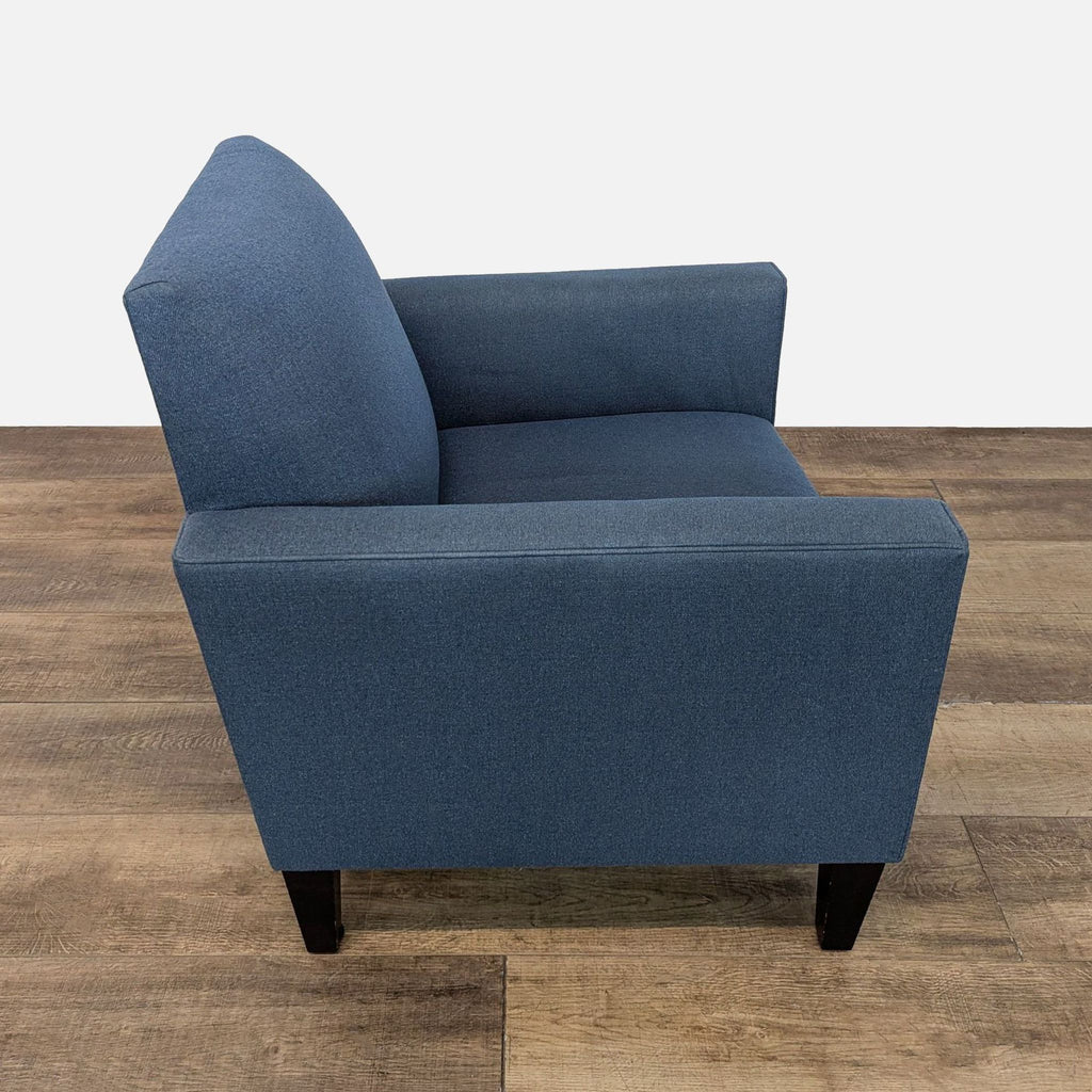 Side view of blue chair with sleek design and wood feet.