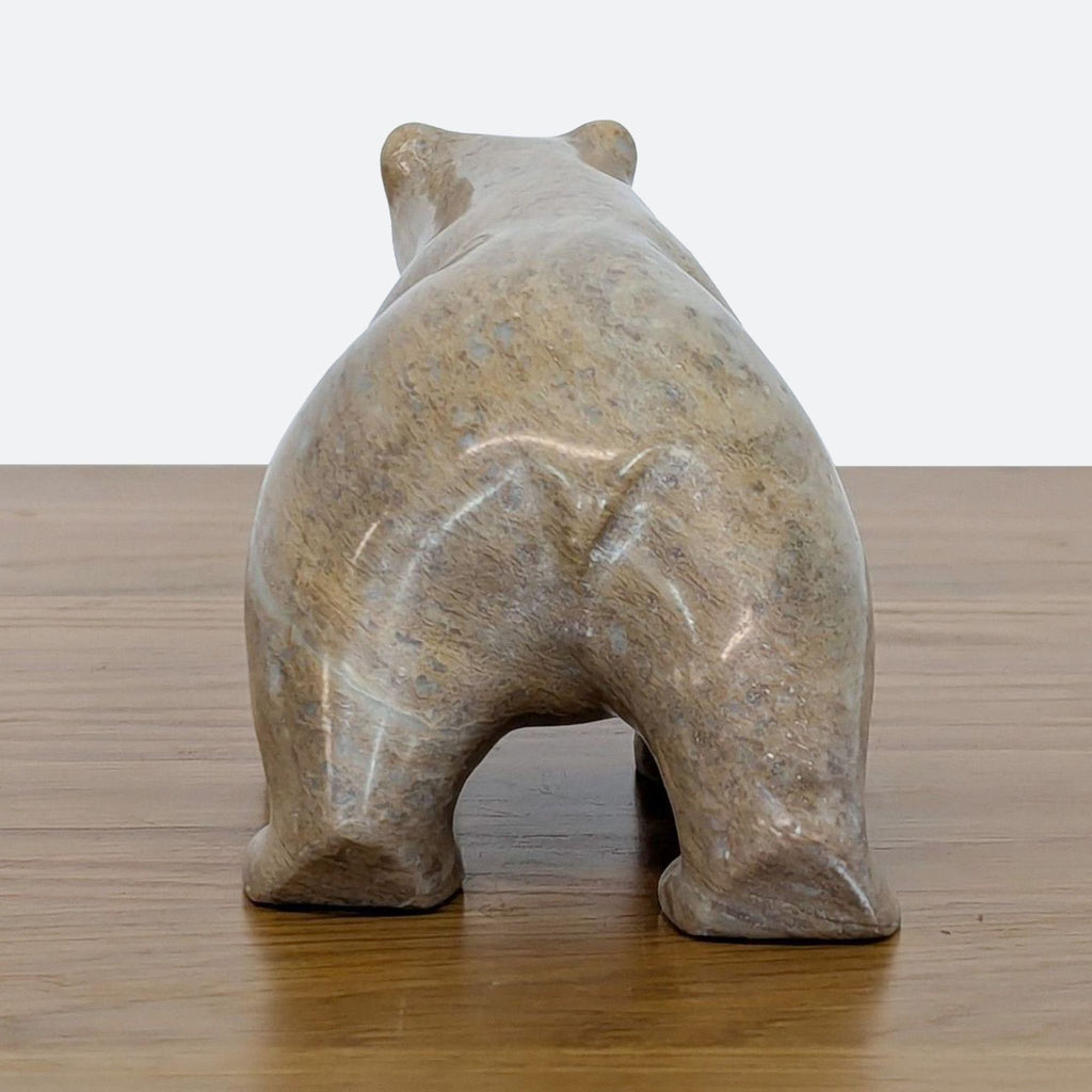 Rear view of a soapstone bear sculpture, showing smooth curves and color variations.