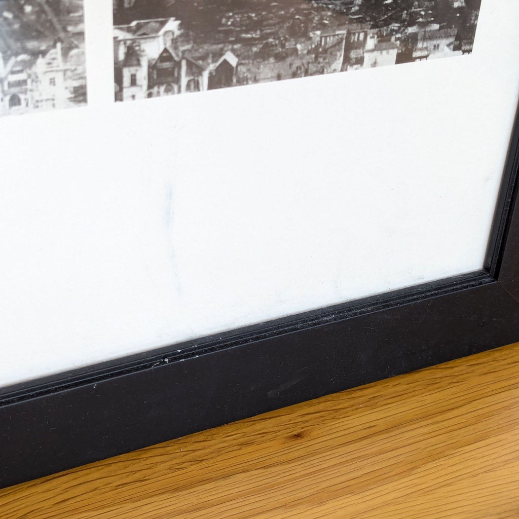 "Close-up of black frame corner on a wooden surface."