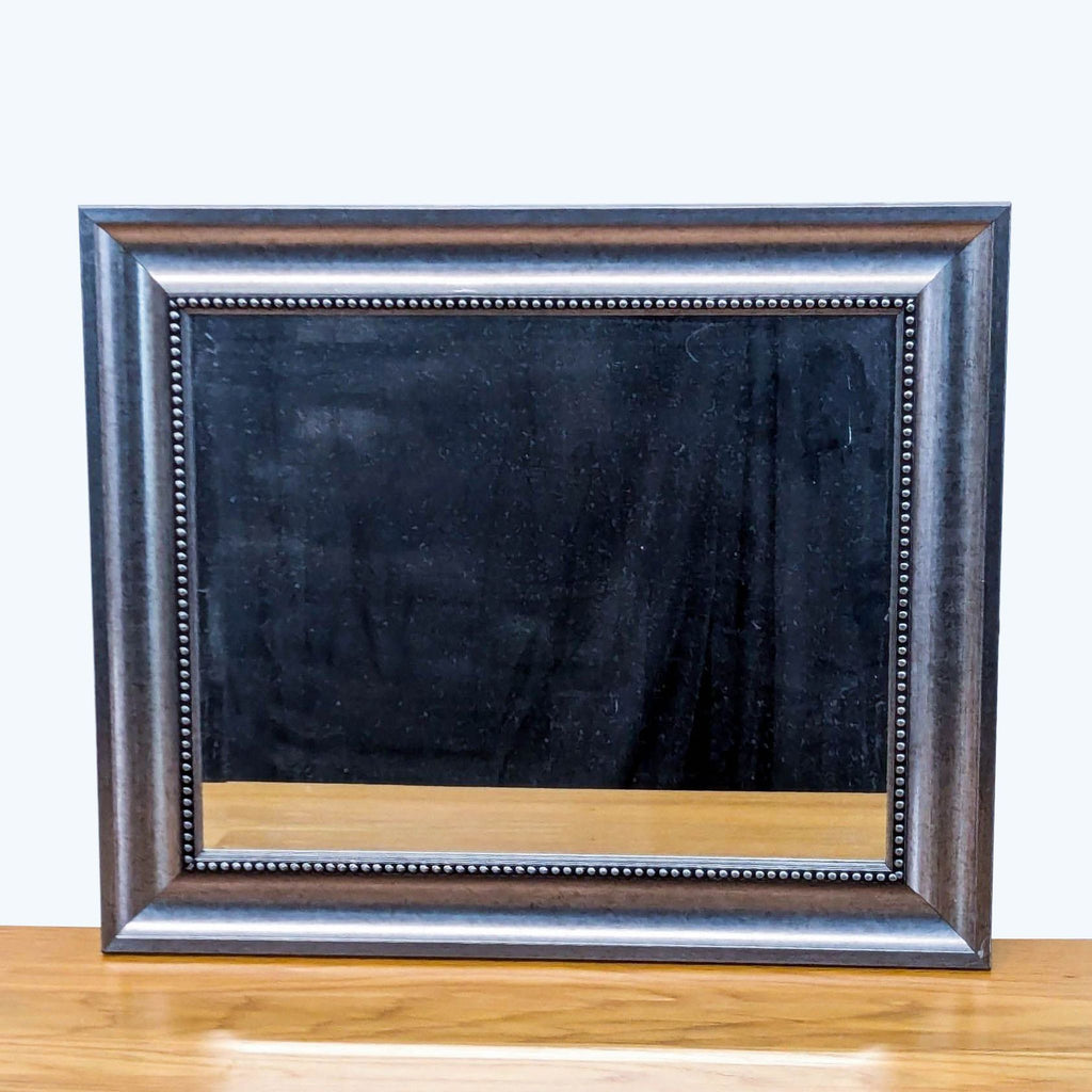 Reperch mirror with a decorative rectangular wooden frame on a tabletop.