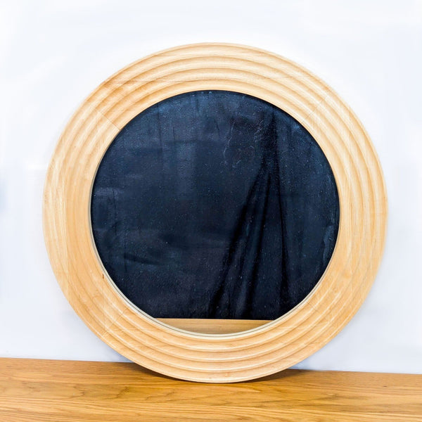 Round mirror with wooden frame and matte black surface.