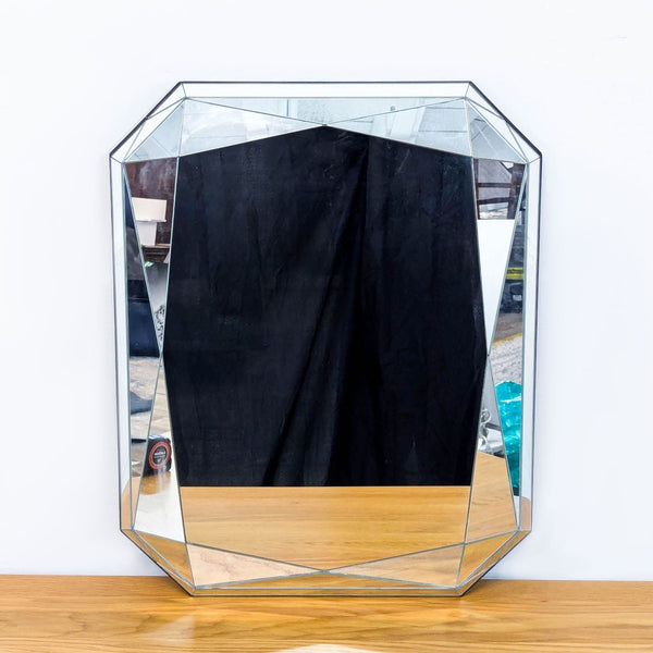 Art Deco style mirror with fully mirrored surface, angled on a wooden table.