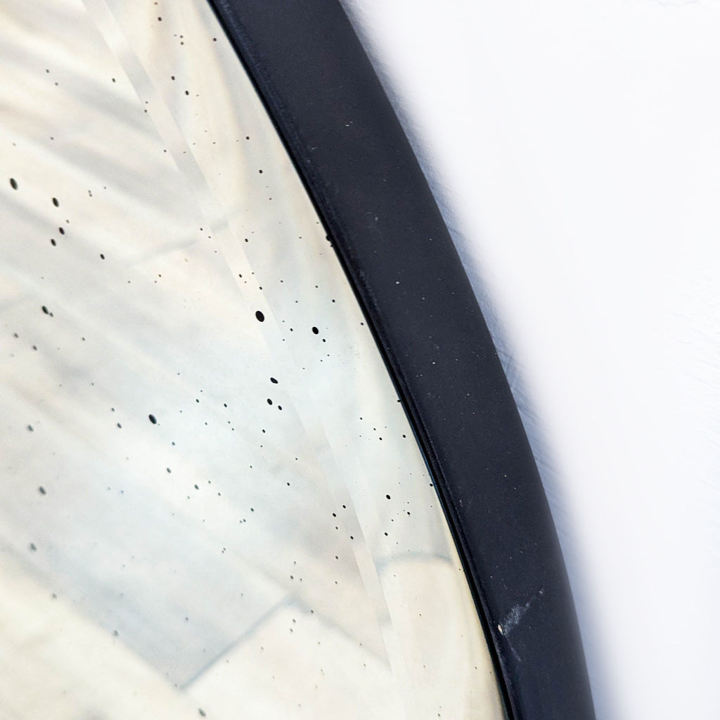 Close-up of a mirror's edge, showing its antiqued texture and dark frame.  