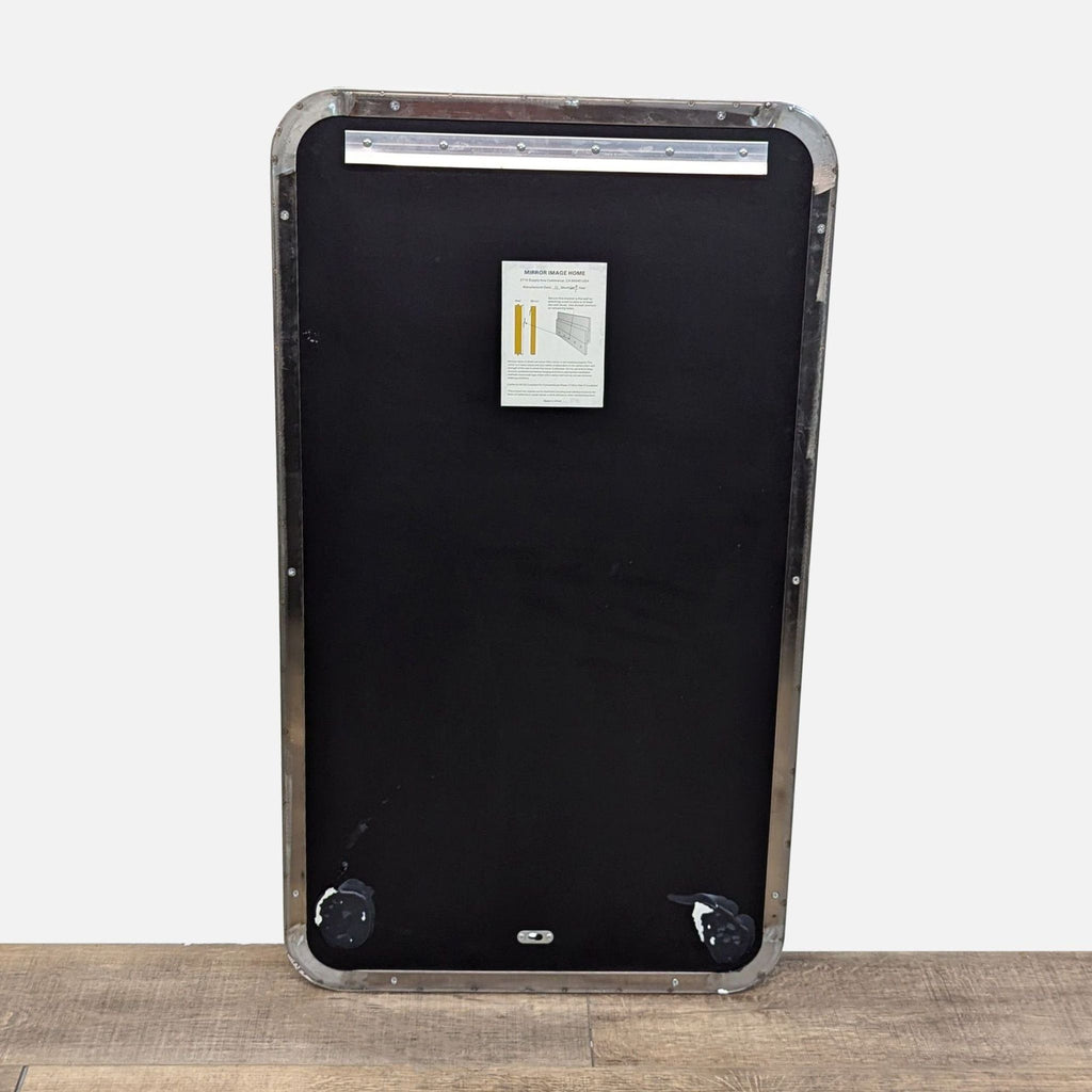 Back of mirror with black panel and mounting instructions attached.
