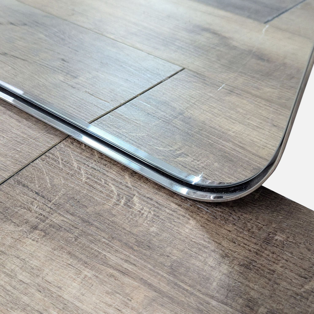 Close-up of the mirror's edge on a wooden surface, showing its sleek design.