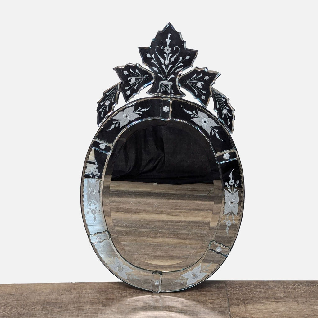 Elegant oval mirror with decorative floral patterns, black border, and an ornate top design.