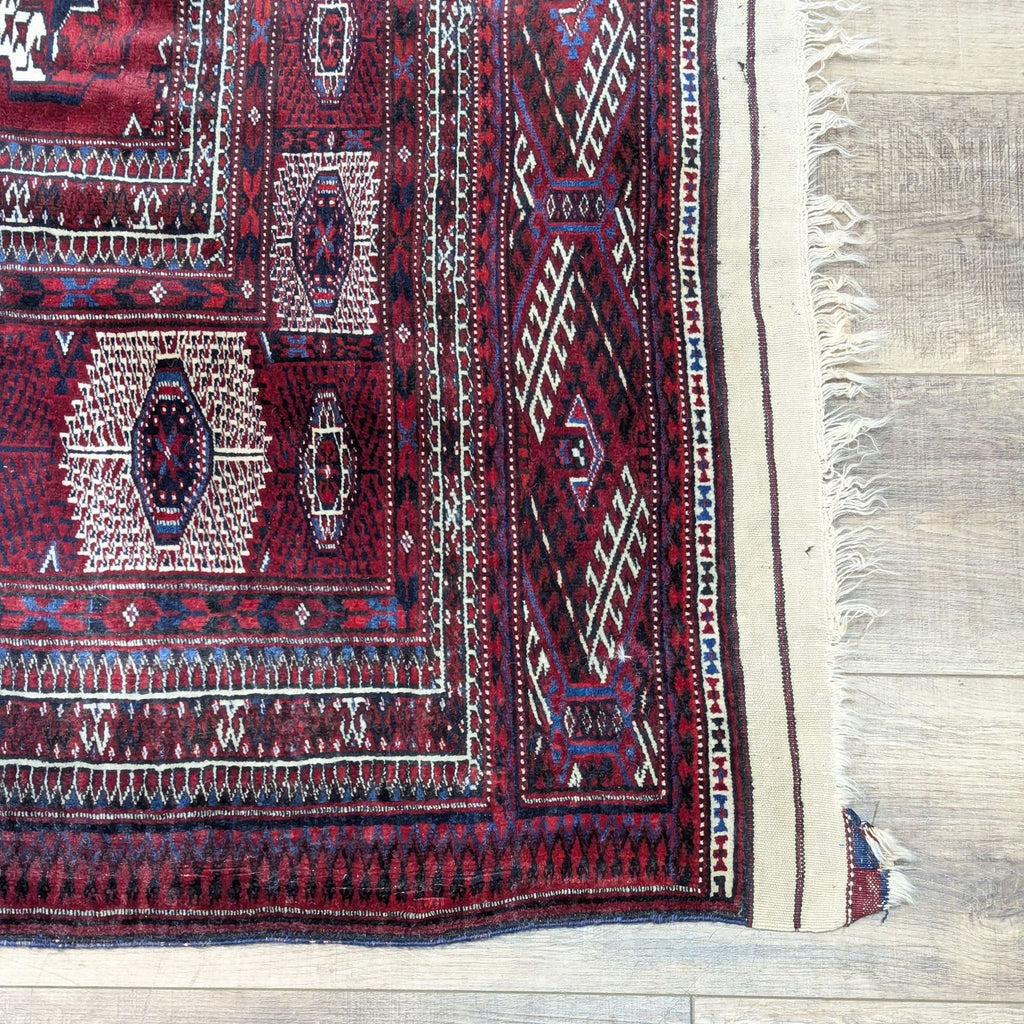 Corner of a Turkmen Afghan rug showing detailed Bukhara patterns and fringe.