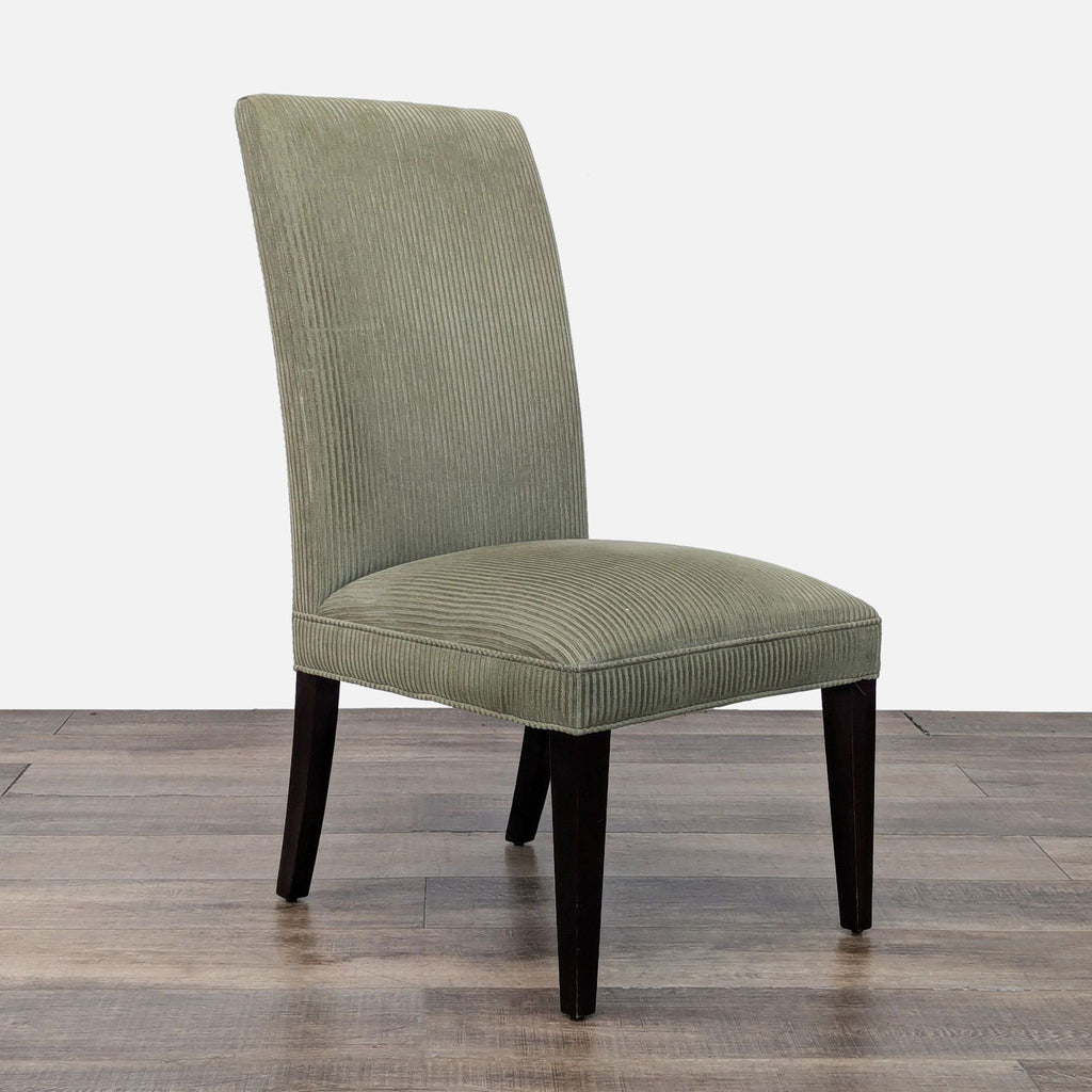 Side angle of a Restoration Hardware dining chair in green fabric with sleek dark legs.