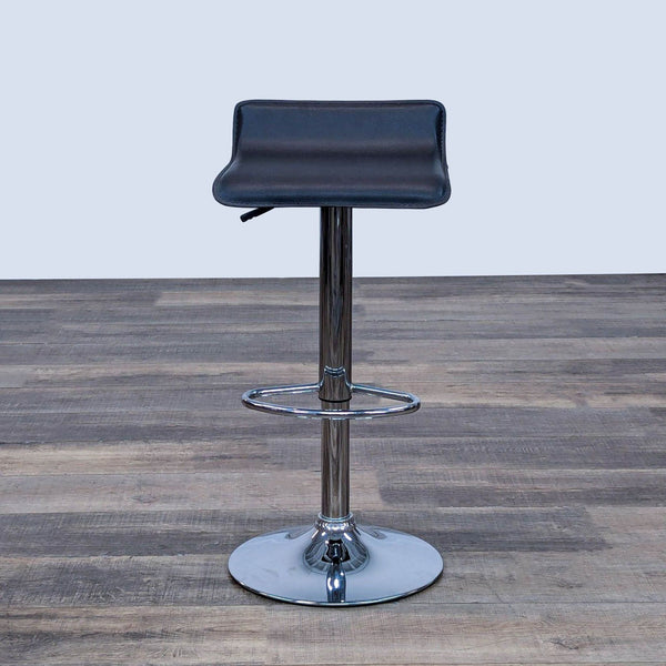 Black stool with faux leather seat, adjustable chrome pole, and footrest on wood floor.