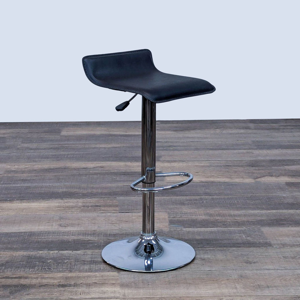 Side view of black stool, chrome adjustable base, and footrest on a wooden surface.