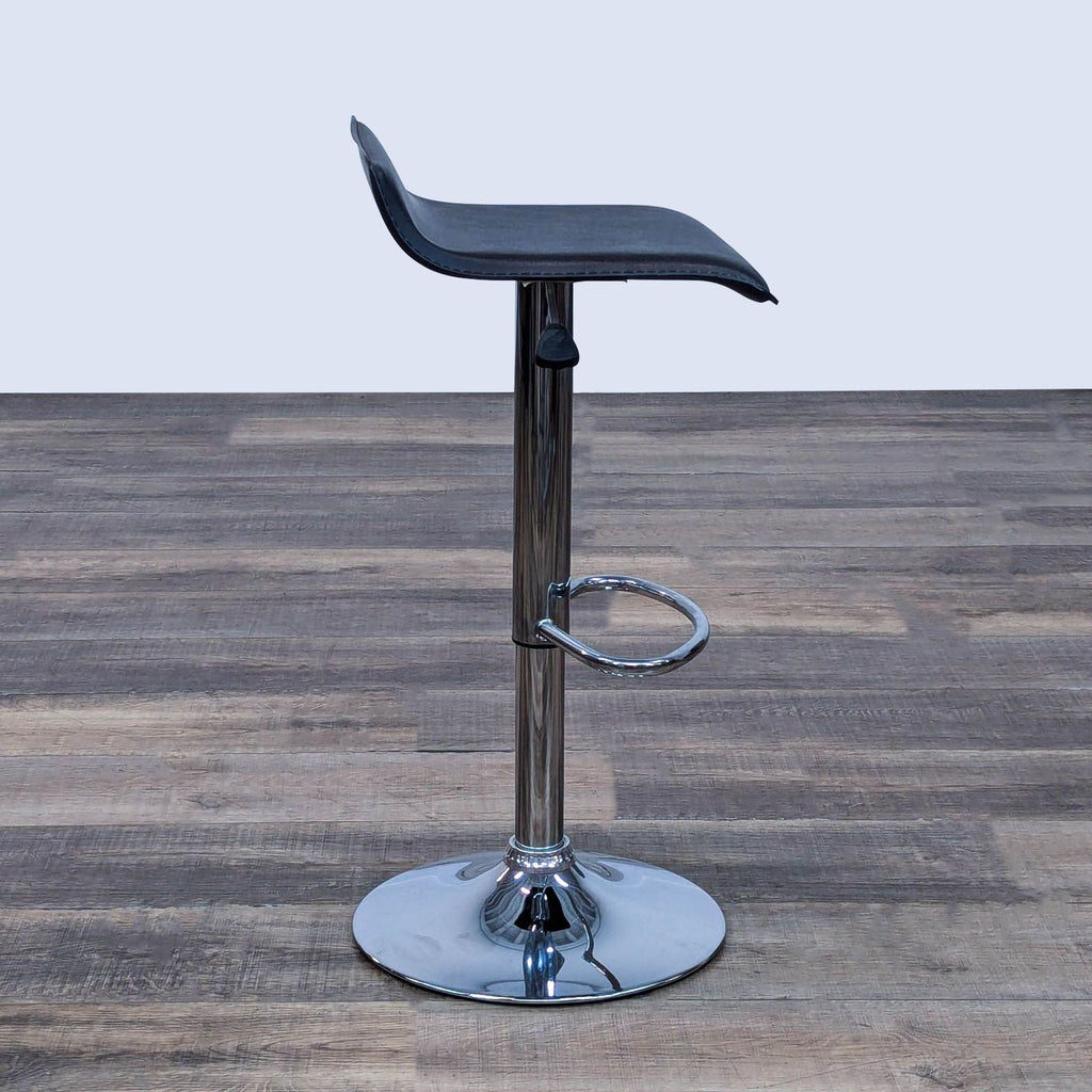 Black faux leather stool, chrome footrest, and adjustable height feature on wood plank flooring.