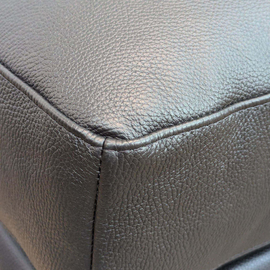 Close-up of black ottoman's textured leather material.