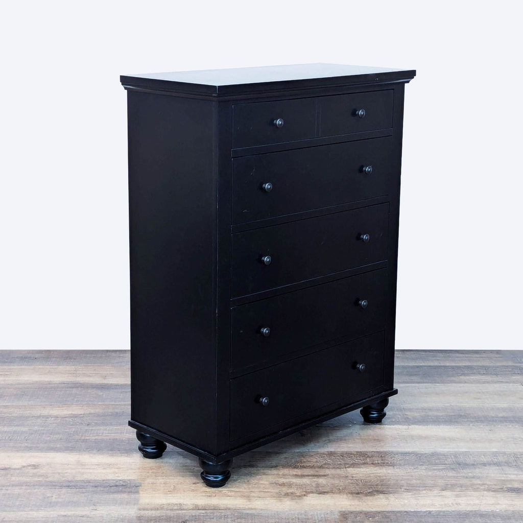 Angled view of black dresser with 5 closed drawers and elegantly turned wood feet.