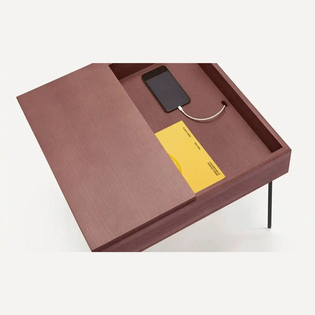 Top view of walnut side table, showing storage with a phone charger and book inside.
