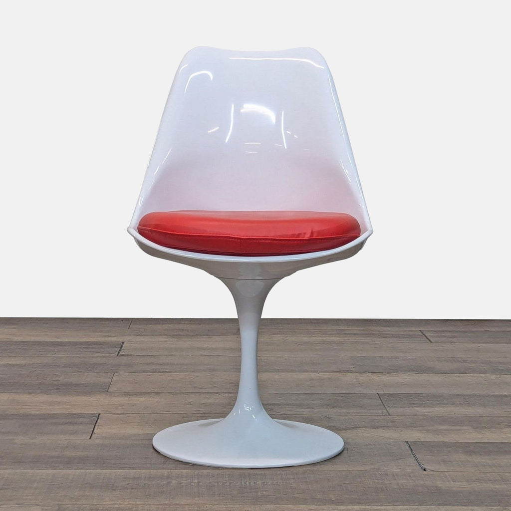 White tulip-style chair with red cushion on wooden floor.