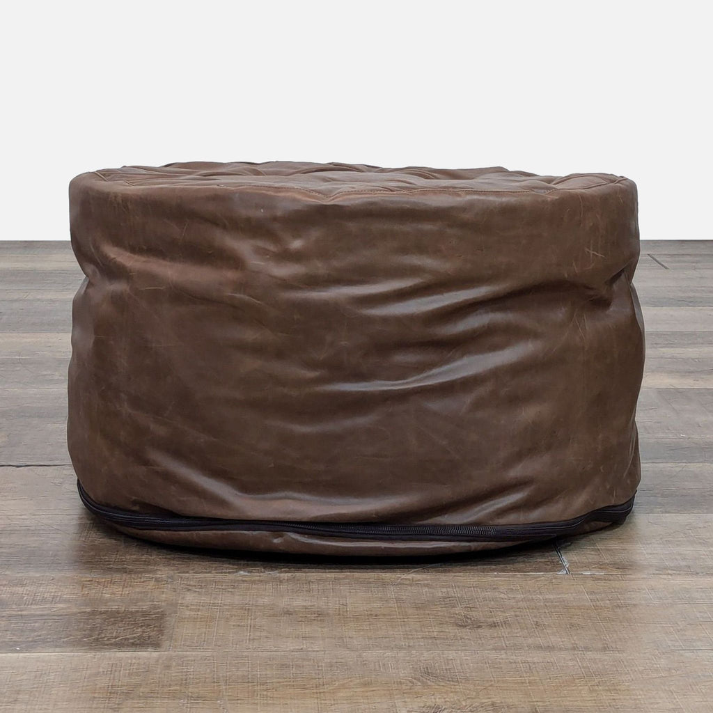 Side view of a brown leather ottoman with visible base zipper.
