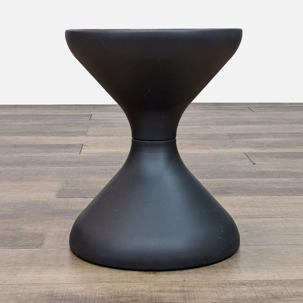 Top view of a round teak table with a black base and ice bucket.  