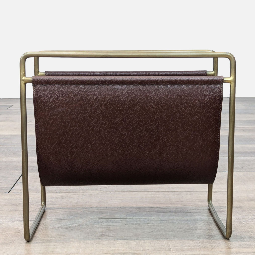 Leather magazine holder with brass-finish iron frame on wood floor.