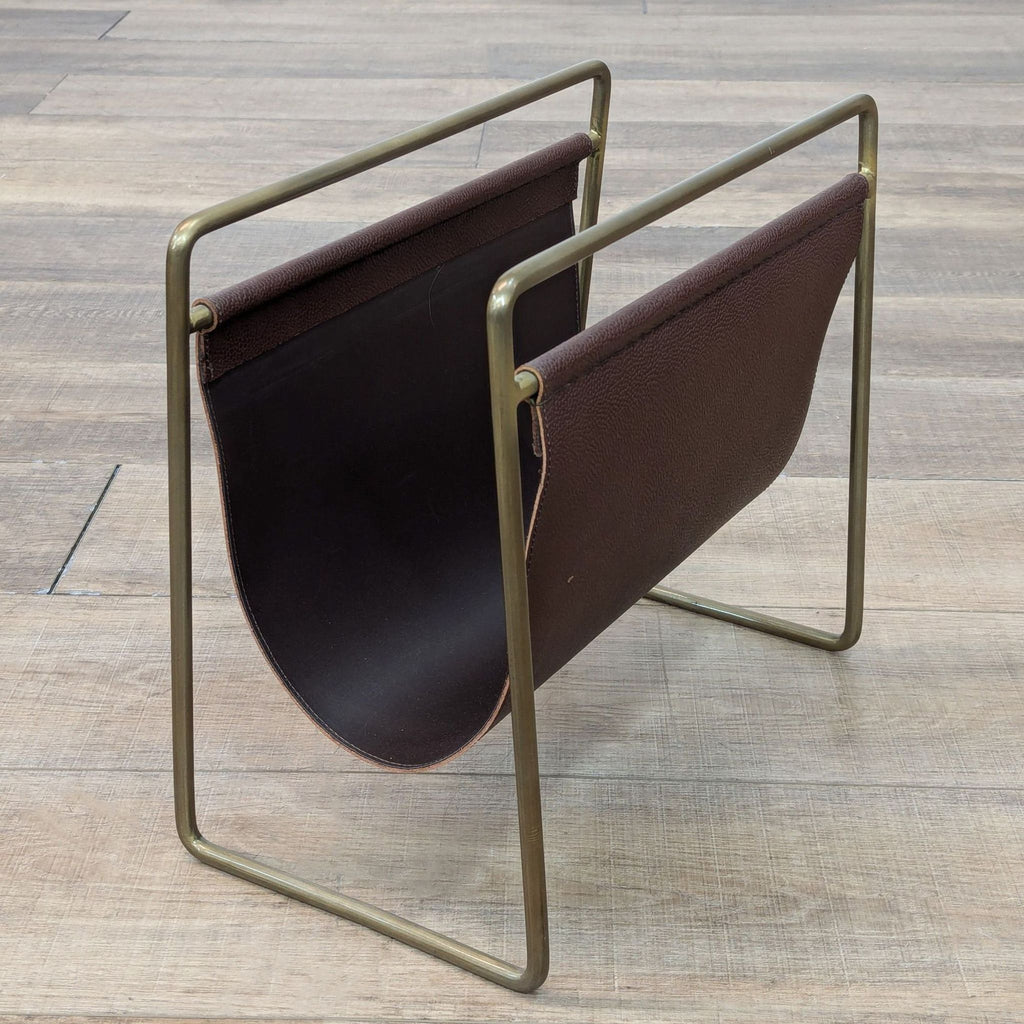 Side view of leather and brass-finish magazine holder on wood floor.