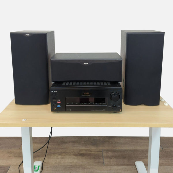 Sony and B&W audio system with two speakers, a center speaker, and amplifier on a table.