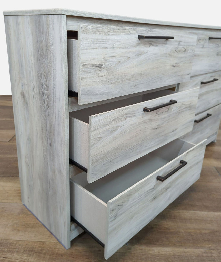 Side view of dresser with partially open drawers showing linear metal pulls.