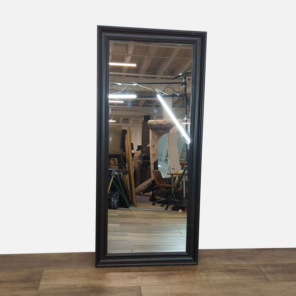 Mirror with a dark frame reflecting an interior room.