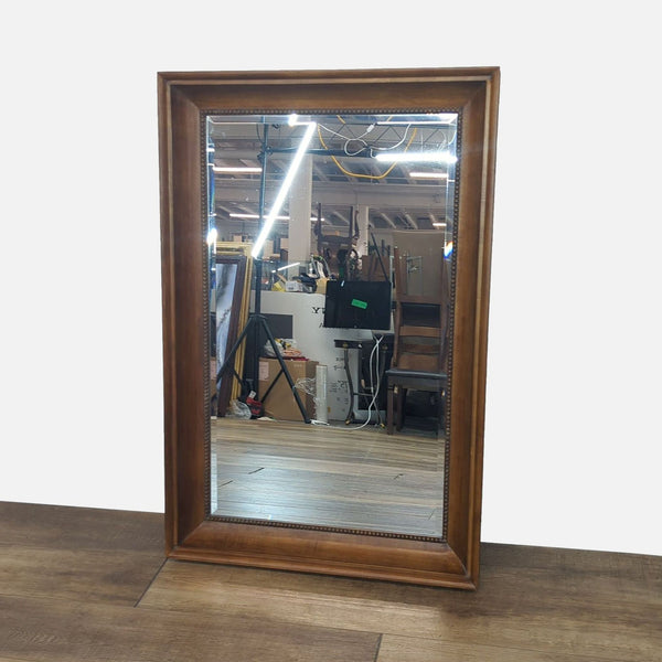 Reperch mirror with a detailed wooden frame, reflecting an indoor setting.