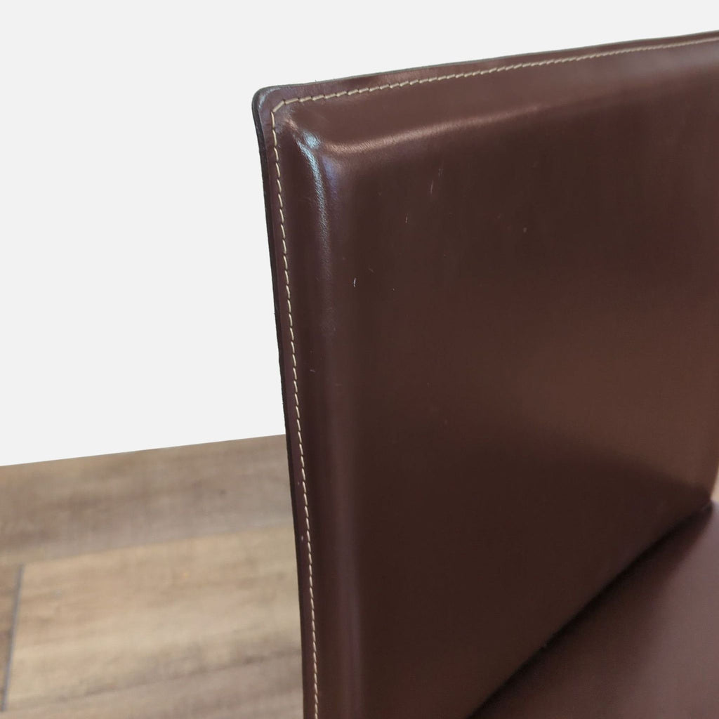 Close-up of the Reperch chair’s leather backrest, highlighting the detailed stitching along the edge.