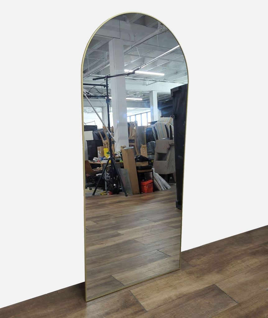 Elegant arched mirror from Reperch, reflecting wooden floor and workshop surroundings.