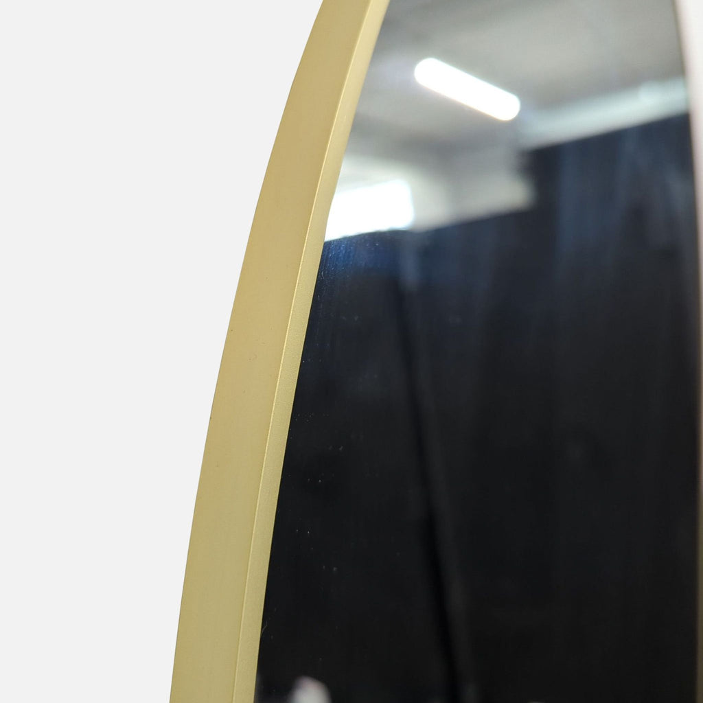 Close-up of the arched mirror's sleek gold frame from Reperch in an industrial environment.