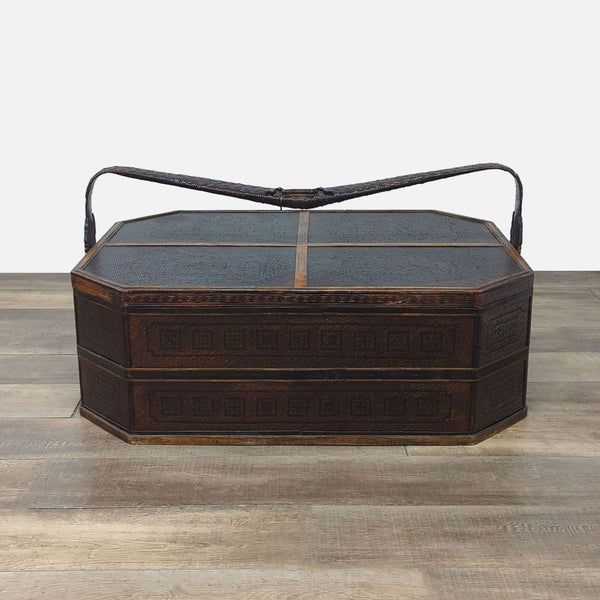 Wicker-covered wooden basket with carved handles, closed, on a wooden floor.