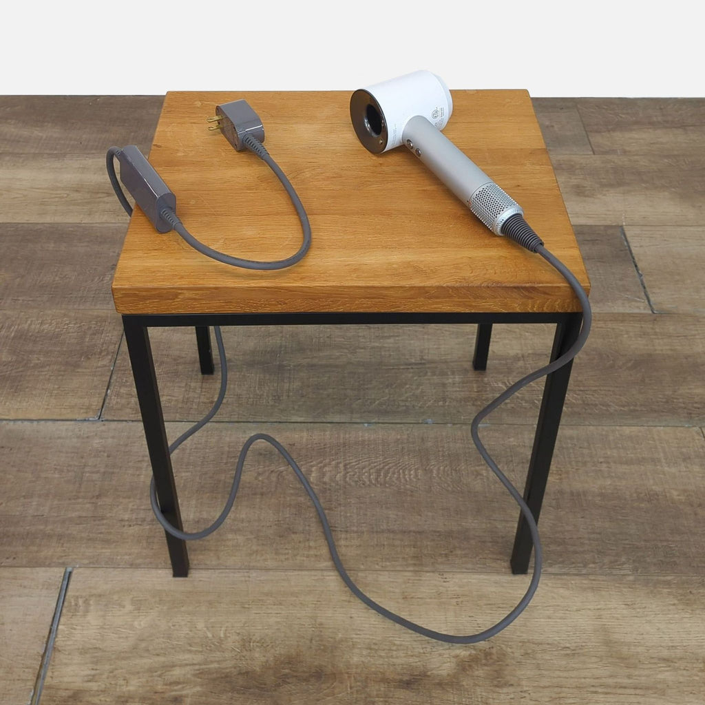 Dyson Supersonic Hairdryer and power cable on a wooden table.
