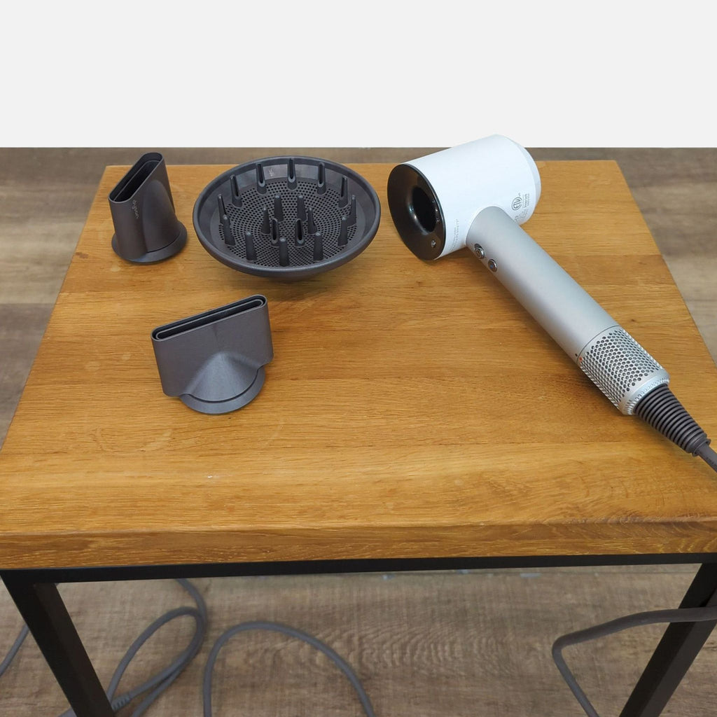 Dyson Supersonic Hairdryer with attachments on a wooden table.