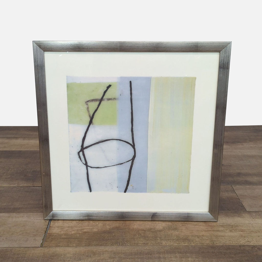 Abstract drawing with lines and shapes in a silver frame on a wooden floor.