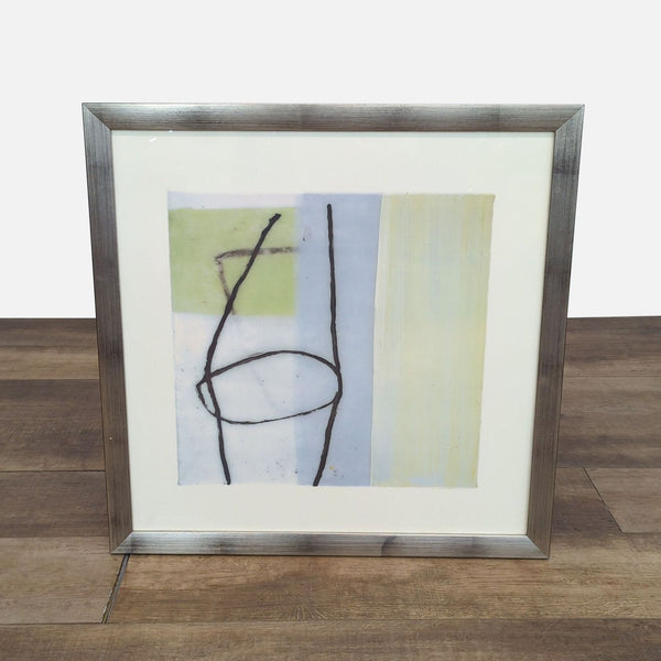 Abstract drawing with lines and shapes in a silver frame on a wooden floor.