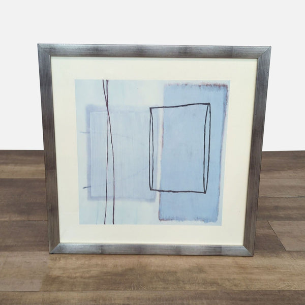 Abstract art print with geometric shapes in silver frame.