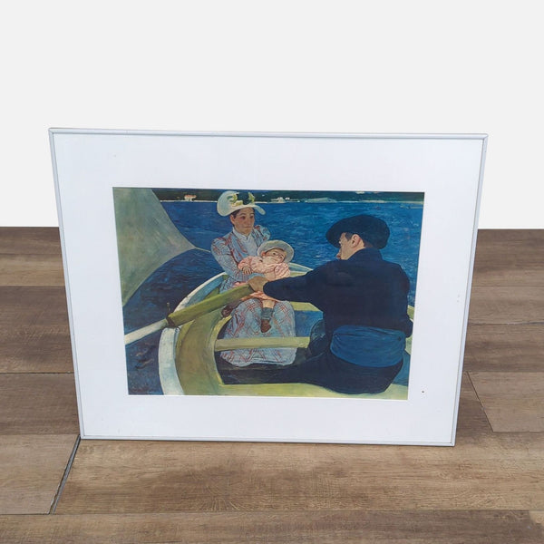 Framed print of "The Boating Party" by Mary Cassatt on a wooden floor.
