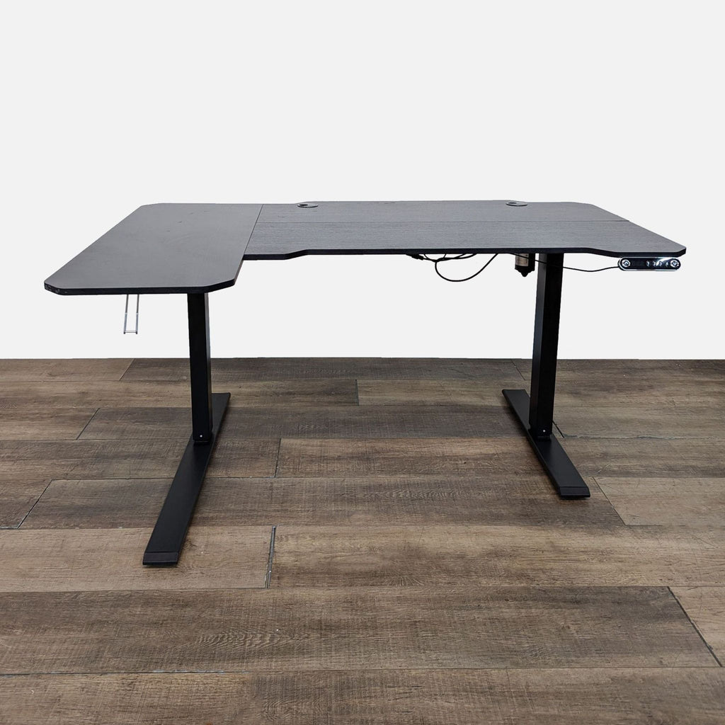 Reperch desk with adjustable metal base and black L-shaped top in a room.
