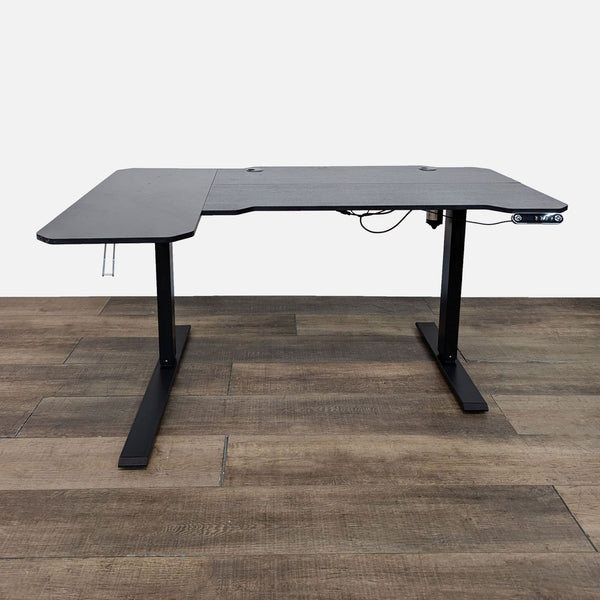 Reperch desk with adjustable metal base and black L-shaped top in a room.