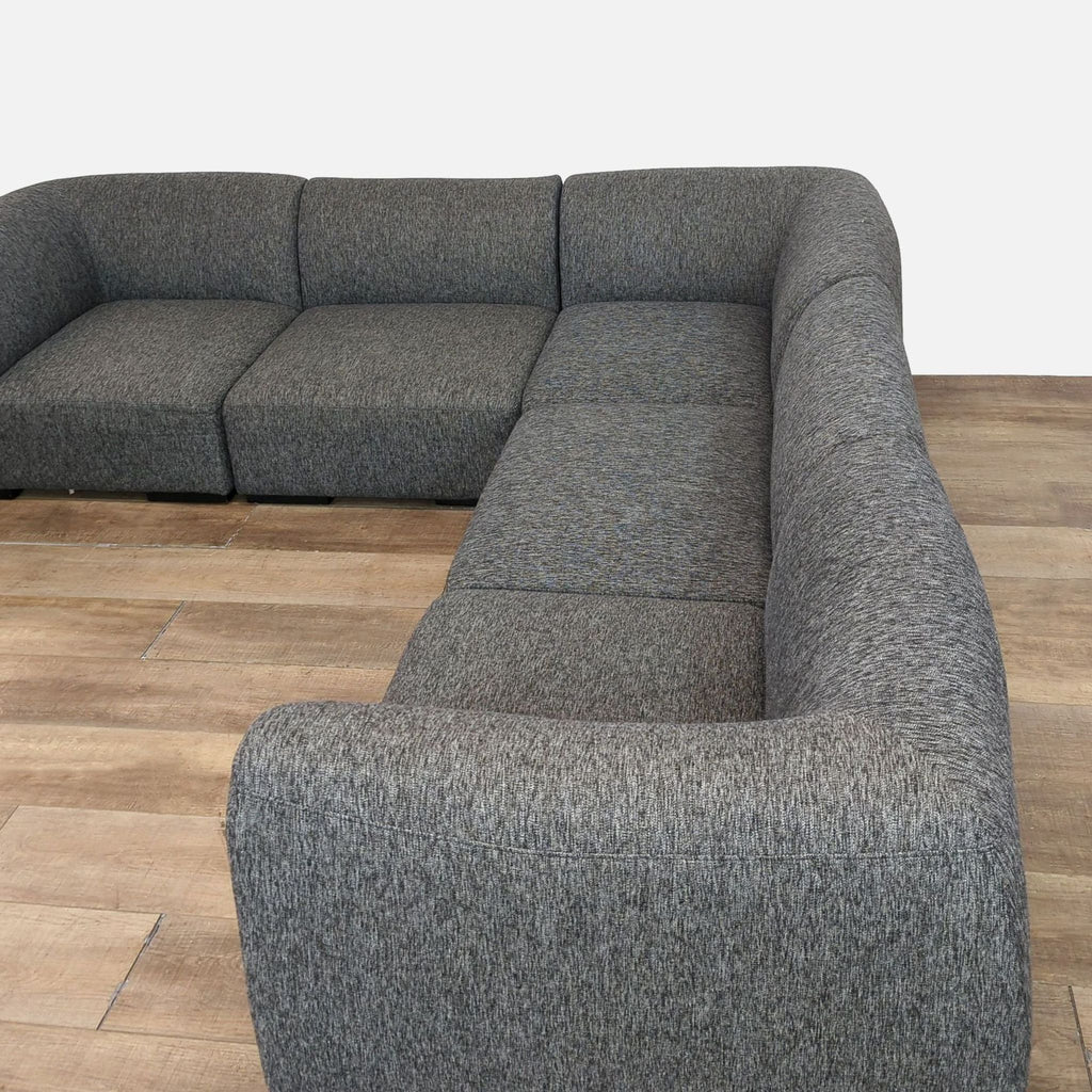Elegant Reperch sectional with gray fabric and wooden floor, showcasing modular design.