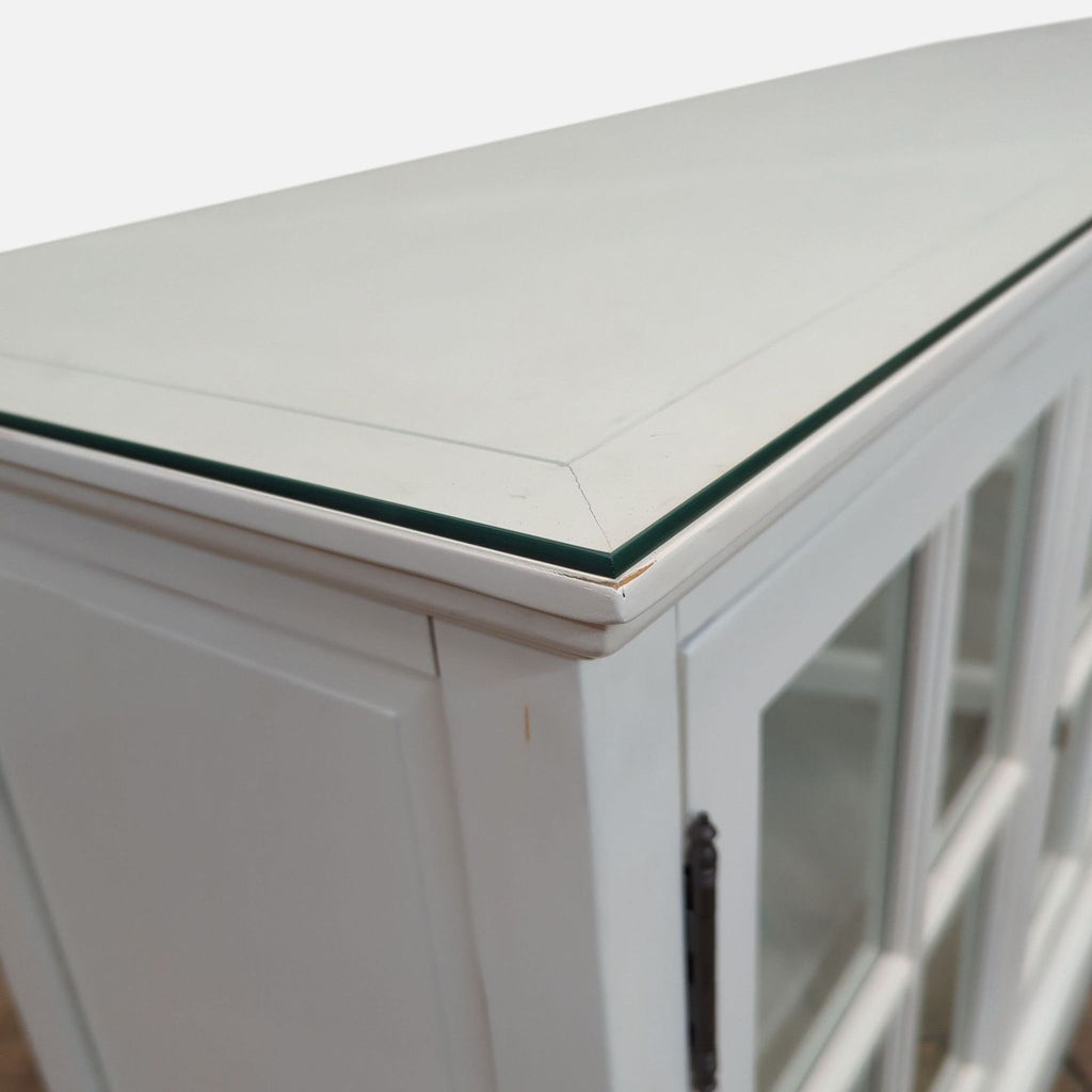 Close-up of glass protective top on white sideboard.